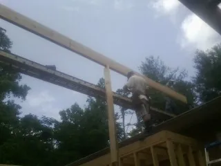 Carpenter setting a ridge beam over a new addition frame — Ice Dam Removal by Roofing Brothers in Northbridge