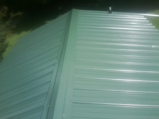 New green metal panels meeting at the ridge of a roof — Flat Roof Repair work by our crew in Northbridge