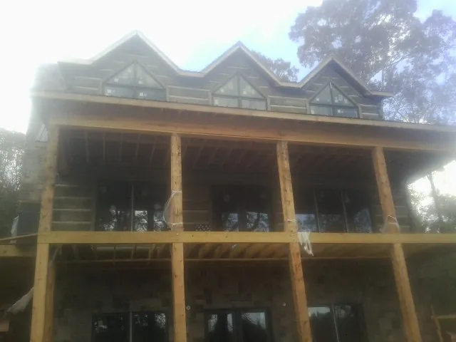 Dormers and porch framing on a large log home under construction — Roof Coating work by our crew in Northbridge