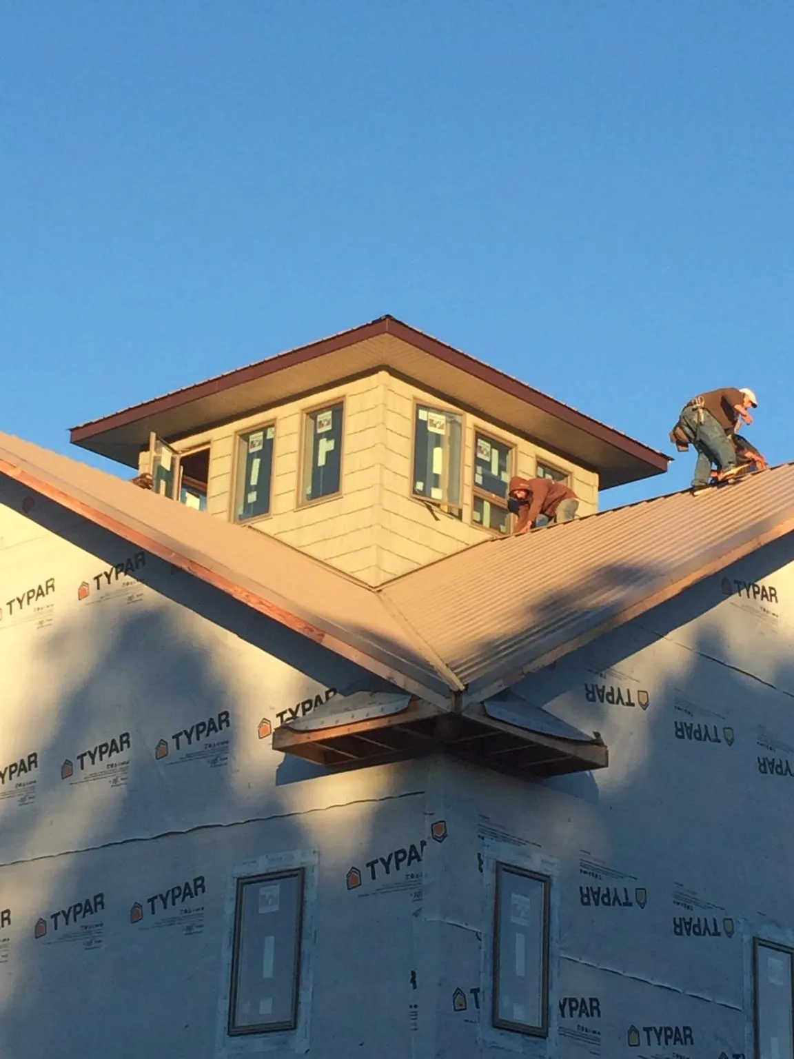 Roofers working around a rooftop cupola on a new metal roof at sunset — Roof Waterproofing in Northbridge by Roofing Brothers